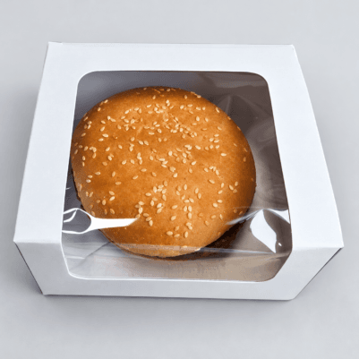 White burger box with a transparent window showcasing a sesame seed burger inside.